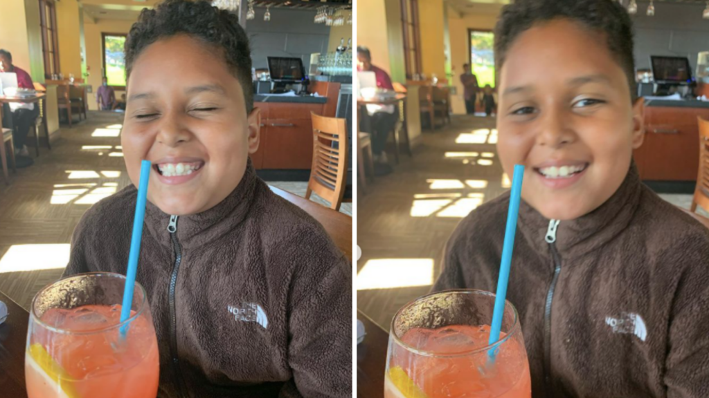 Niema's nephew Angel sips strawberry lemonade and smiles joyfully. He is wearing a brown Northface fleece. 