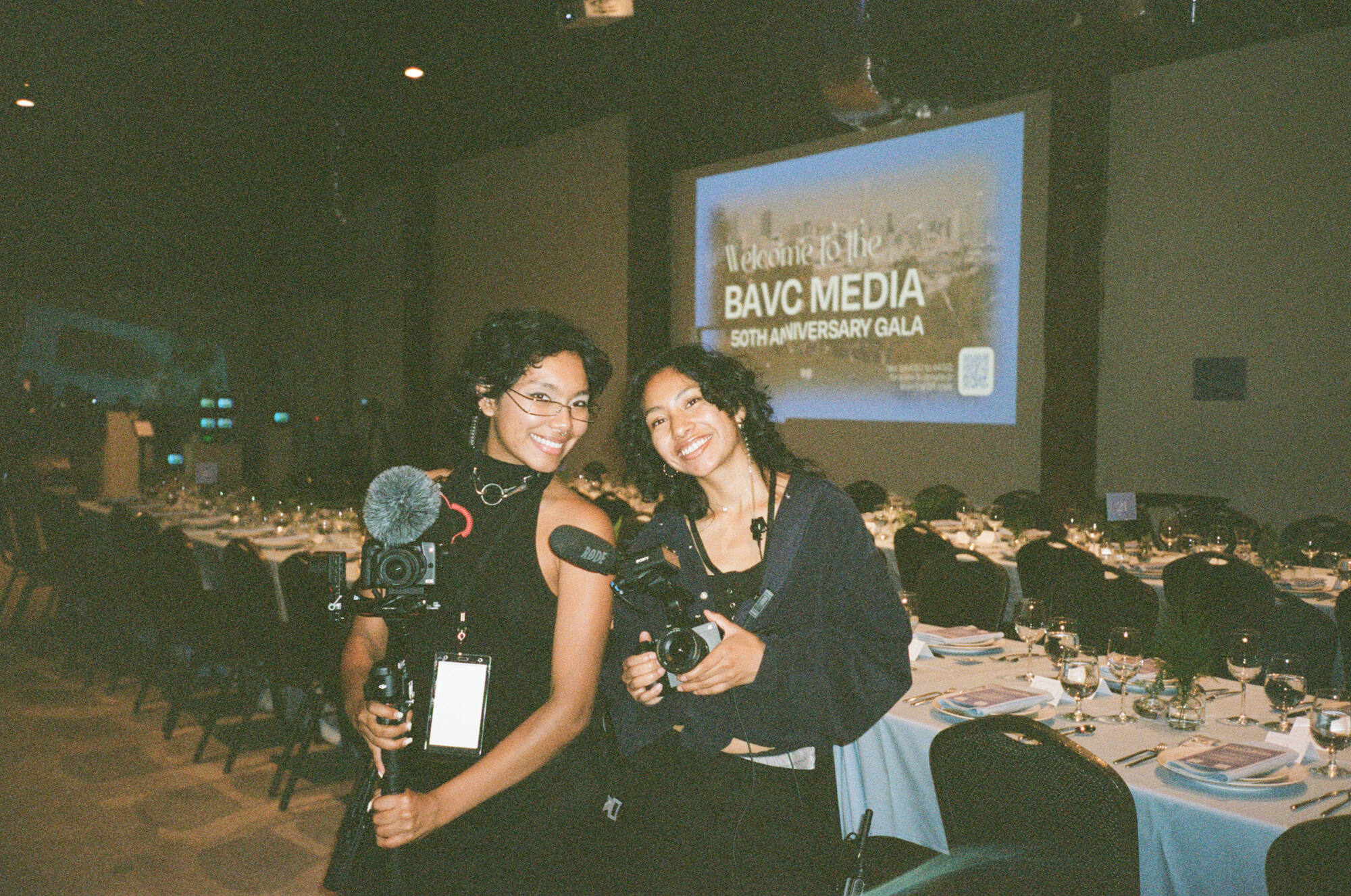 A young Black woman operates a camera during an event.